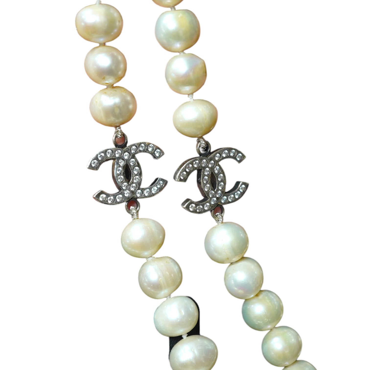 A modern long single strand cultured pearl necklace, with paste set white metal 'double C' clasps, 124cm. Condition - fair